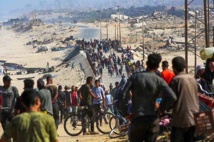 Palestinians gather on a street in Nuseirat in the central Gaza Strip on October 10, 2025. Gaza's civil defence agency said on October 10 that Israeli forces have begun pulling back from parts of the territory, particularly in Gaza City and Khan Yunis. Israeli prime minister's office said that the government had "approved the framework" of a hostage release deal with Hamas, as both sides edged closer to ending more than two years of hostilities in Gaza.